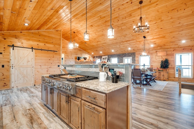 kitchen featuring a barn door, wood walls, light wood-type flooring, and pendant lighting