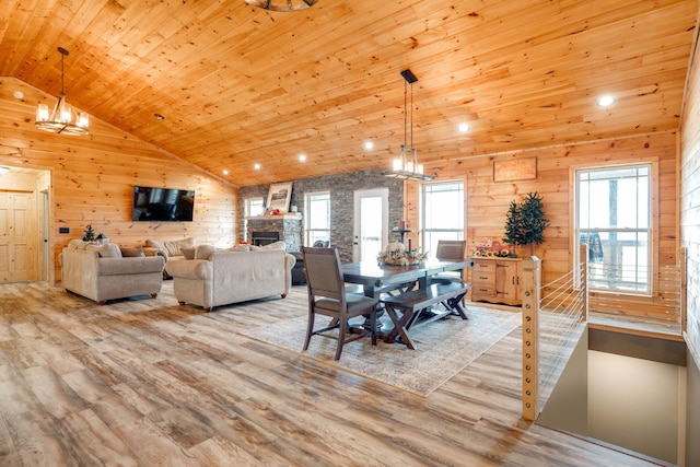 dining room featuring wood ceiling, wood walls, light hardwood / wood-style floors, and plenty of natural light