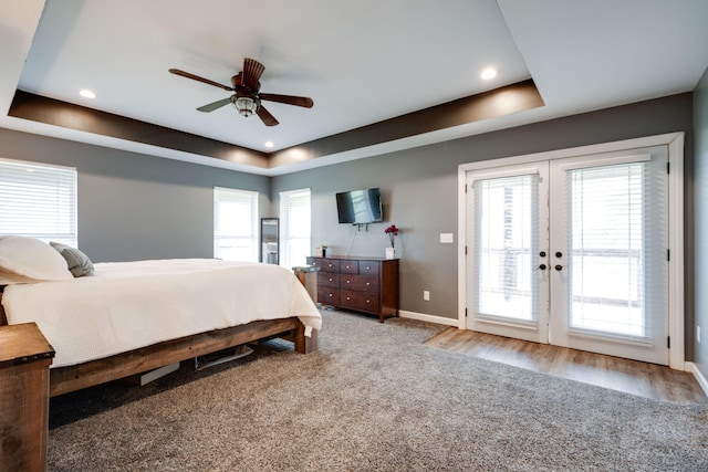 bedroom with ceiling fan, a raised ceiling, access to exterior, and multiple windows