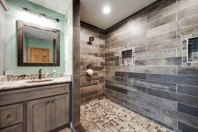 bathroom featuring a tile shower and vanity