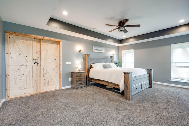 carpeted bedroom with ceiling fan and a raised ceiling