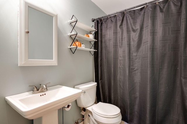 bathroom featuring sink, toilet, and curtained shower