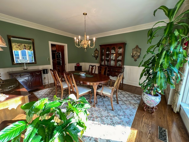 dining area featuring hardwood / wood-style flooring, crown molding, and a notable chandelier