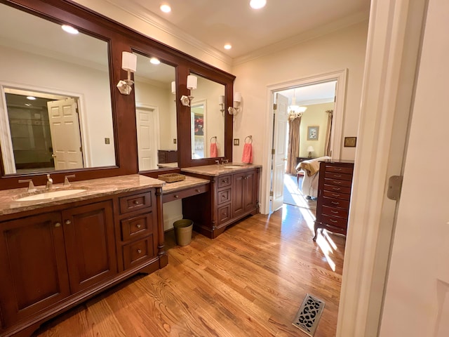 bathroom featuring hardwood / wood-style flooring, vanity, crown molding, and a chandelier