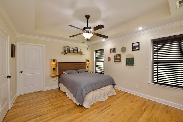 bedroom featuring ornamental molding, a tray ceiling, light hardwood / wood-style floors, and ceiling fan