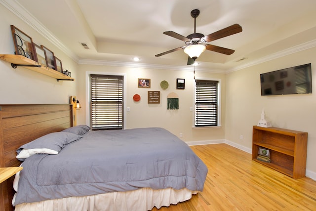 bedroom featuring crown molding, light hardwood / wood-style floors, ceiling fan, and a raised ceiling