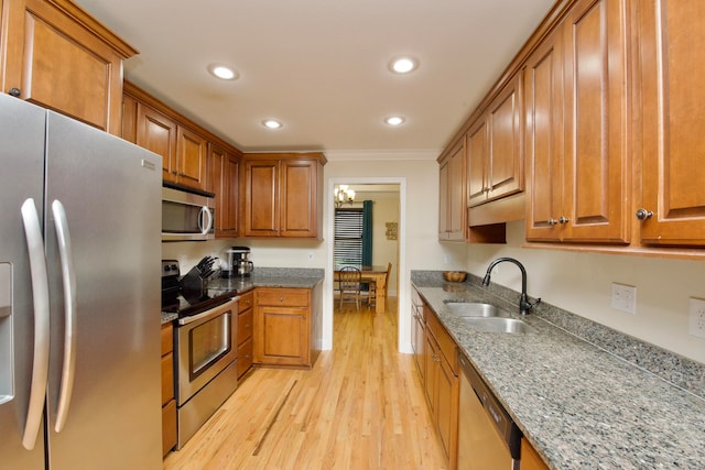 kitchen featuring sink, ornamental molding, light hardwood / wood-style flooring, appliances with stainless steel finishes, and a notable chandelier