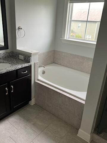 bathroom with tile patterned flooring, vanity, and a relaxing tiled tub