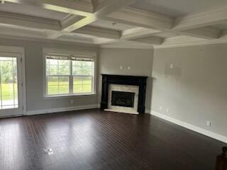 unfurnished living room featuring coffered ceiling, ornamental molding, beam ceiling, and dark wood-type flooring