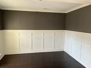 empty room featuring ornamental molding and dark hardwood / wood-style flooring