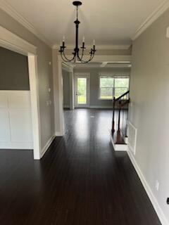 unfurnished dining area featuring a notable chandelier, dark hardwood / wood-style floors, and crown molding