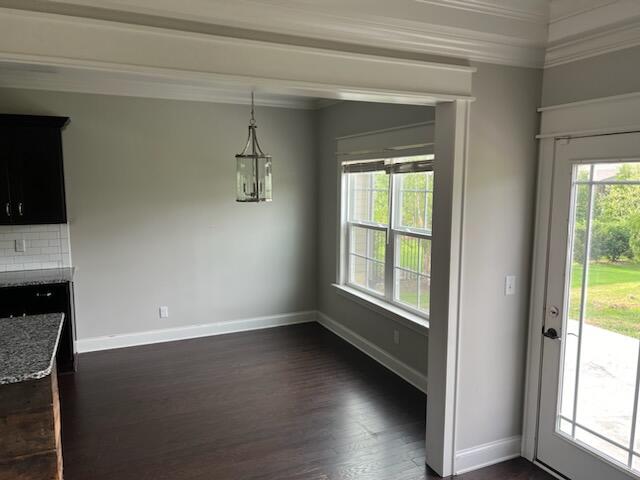 unfurnished dining area with ornamental molding and dark wood-type flooring