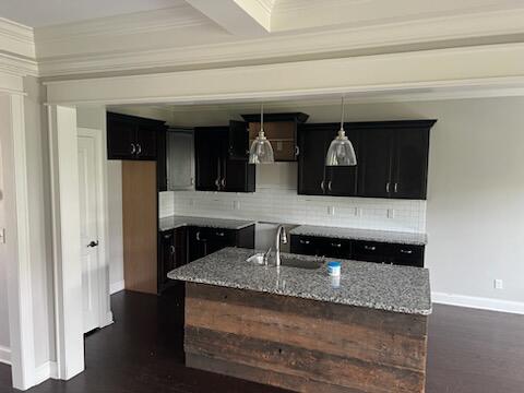 kitchen featuring light stone counters, dark wood-type flooring, tasteful backsplash, sink, and ornamental molding