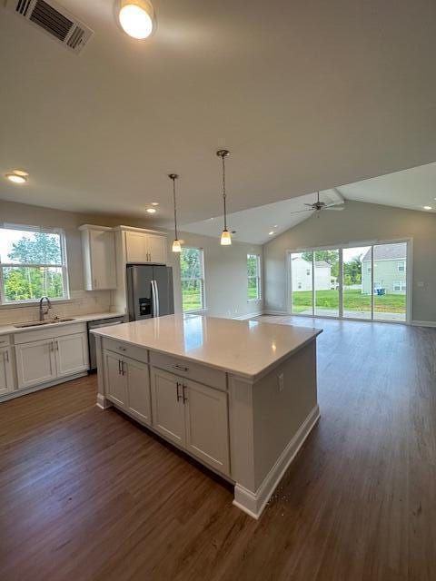 kitchen with lofted ceiling, a wealth of natural light, stainless steel refrigerator with ice dispenser, and ceiling fan