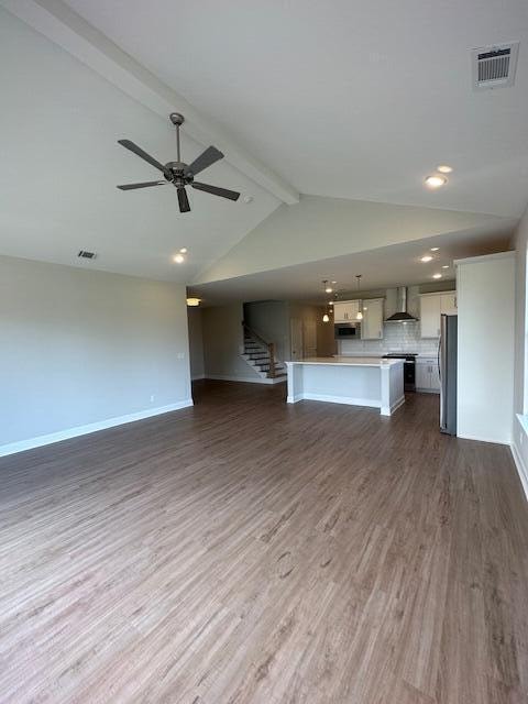 unfurnished living room with vaulted ceiling with beams, dark hardwood / wood-style floors, and ceiling fan