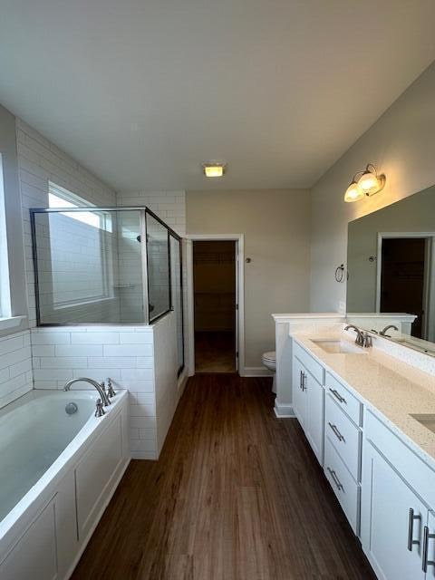 full bathroom with wood-type flooring, separate shower and tub, vanity, and toilet