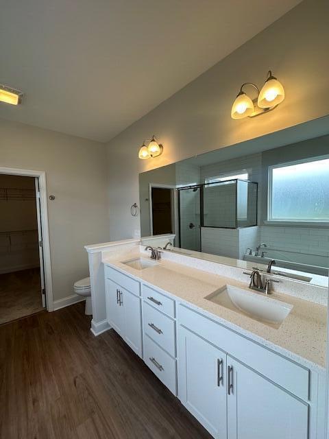 bathroom with hardwood / wood-style floors, vanity, toilet, and an enclosed shower