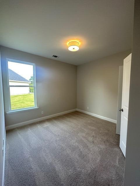 unfurnished room with dark colored carpet