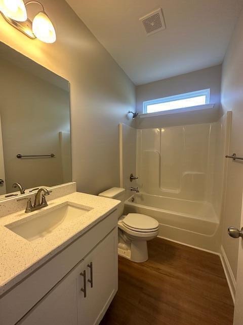 full bathroom with vanity, lofted ceiling, shower / bath combination, hardwood / wood-style flooring, and toilet