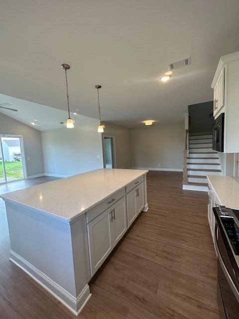 kitchen with hanging light fixtures, white cabinetry, dark wood-type flooring, a kitchen island, and stainless steel range with electric cooktop