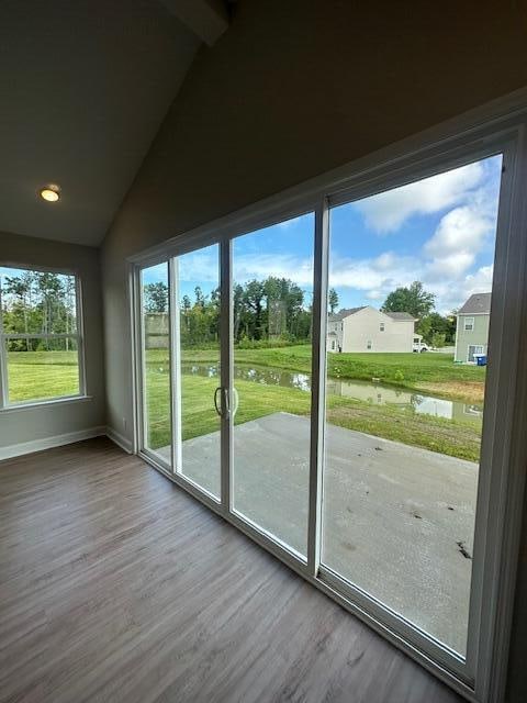 doorway to outside with hardwood / wood-style flooring, lofted ceiling with beams, and a water view