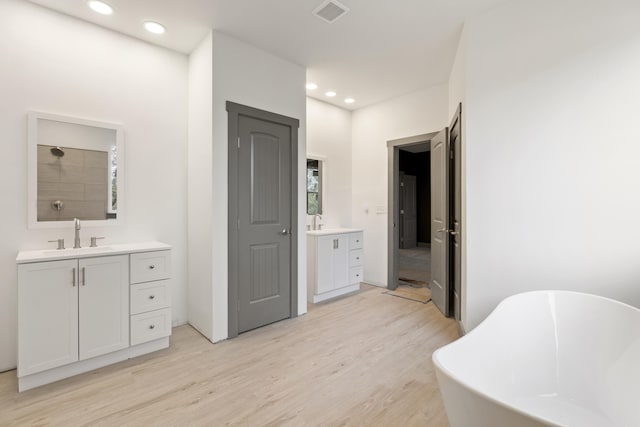 bathroom with hardwood / wood-style flooring, a washtub, and vanity