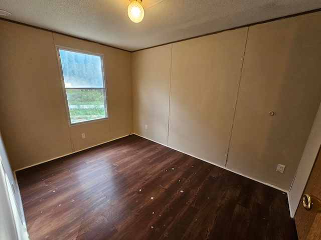 unfurnished bedroom featuring a textured ceiling and dark hardwood / wood-style flooring