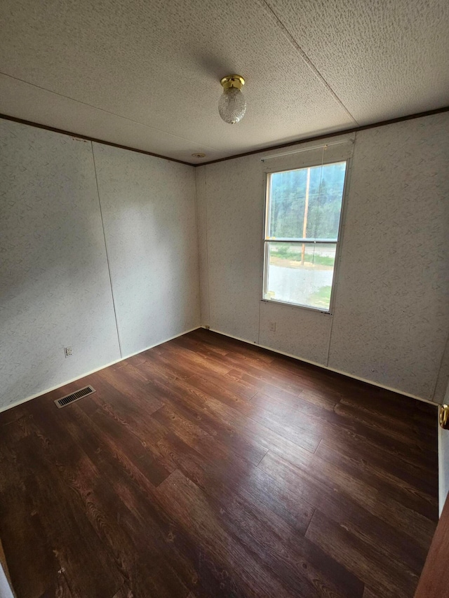 spare room with a textured ceiling and dark wood-type flooring