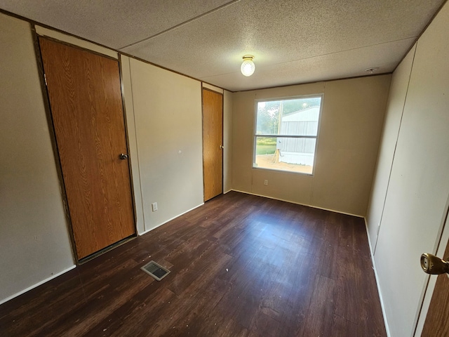 unfurnished bedroom with a textured ceiling, a closet, and dark hardwood / wood-style flooring