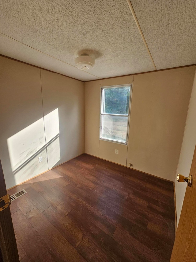 spare room with a textured ceiling and dark hardwood / wood-style floors