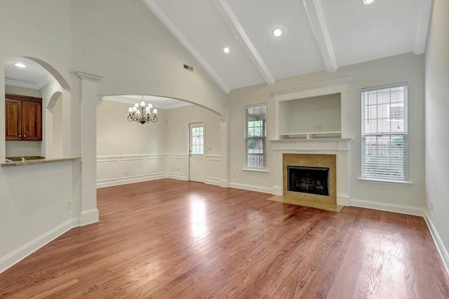 unfurnished living room with wood-type flooring, a high end fireplace, a chandelier, and crown molding