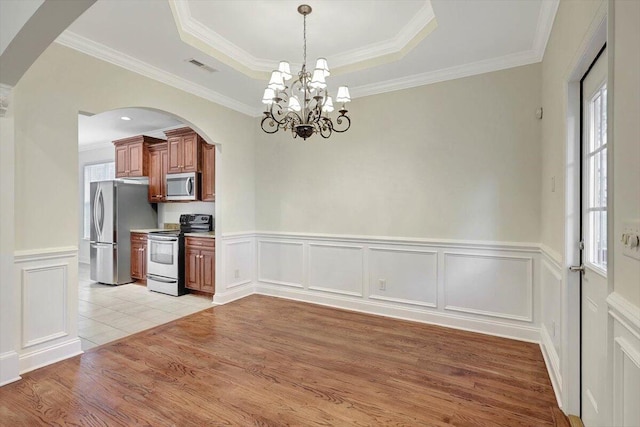 interior space with light hardwood / wood-style flooring, an inviting chandelier, a tray ceiling, and ornamental molding