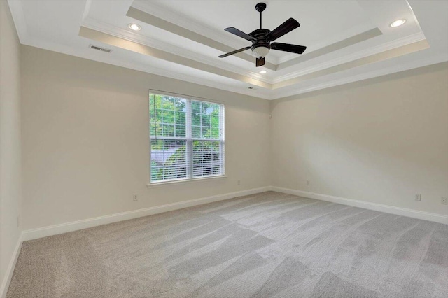 unfurnished room featuring ceiling fan, a tray ceiling, light carpet, and ornamental molding