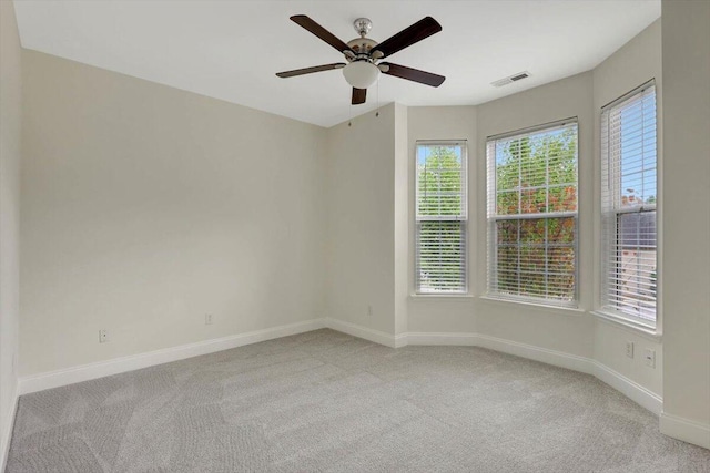 empty room with ceiling fan, light colored carpet, and plenty of natural light