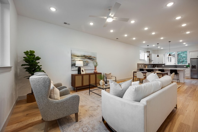 living area featuring recessed lighting, light wood-style floors, ceiling fan, visible vents, and baseboards