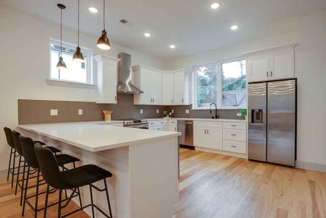 724 W Bell Ave # 110, Chattanooga, TN 37405 - kitchen with white cabinetry, a sink, stainless steel appliances, wall chimney exhaust hood, and a peninsula