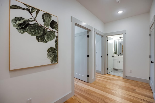 hall with recessed lighting, light wood finished floors, and baseboards