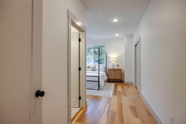 hallway with baseboards, recessed lighting, and light wood-style floors