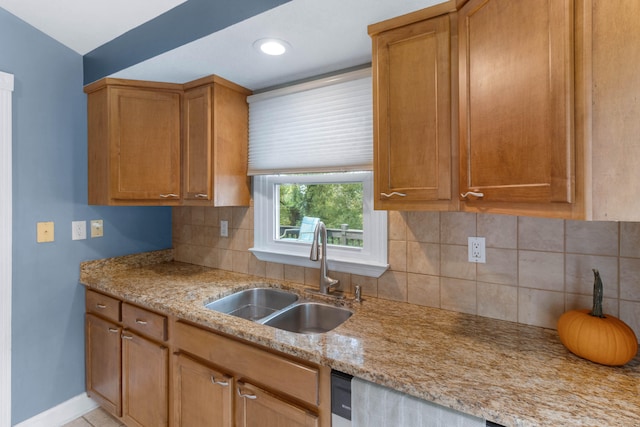 kitchen with light stone counters, sink, and tasteful backsplash