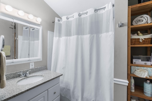 bathroom featuring vanity, lofted ceiling, and a shower with shower curtain