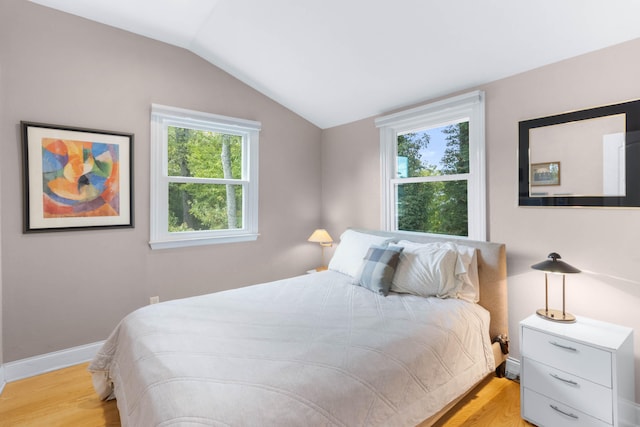 bedroom with multiple windows, vaulted ceiling, and light hardwood / wood-style flooring