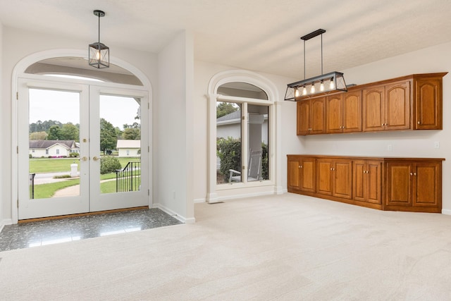 interior space with light carpet, decorative light fixtures, and french doors