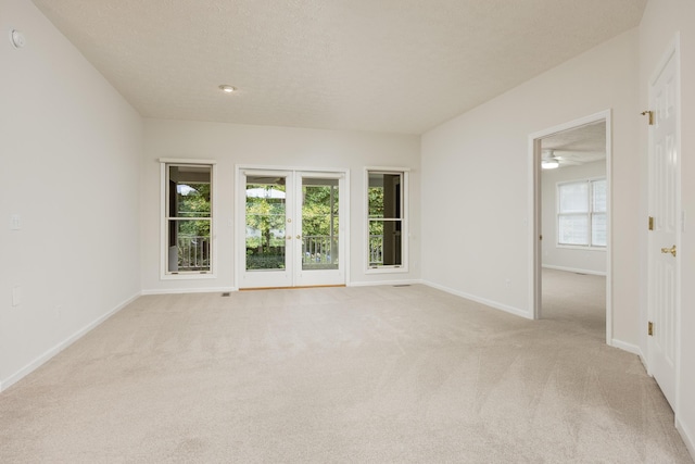 carpeted empty room with a textured ceiling, ceiling fan, and plenty of natural light