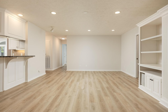 unfurnished living room featuring a textured ceiling and light hardwood / wood-style flooring