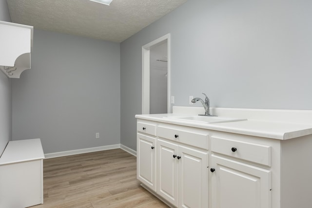 bathroom with a textured ceiling, wood-type flooring, and vanity