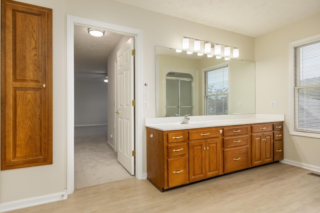 bathroom with a textured ceiling, wood-type flooring, vanity, and an enclosed shower