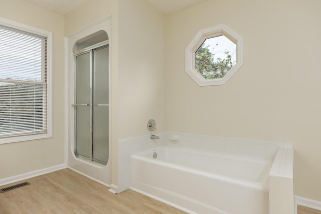 bathroom featuring wood-type flooring, separate shower and tub, and a healthy amount of sunlight