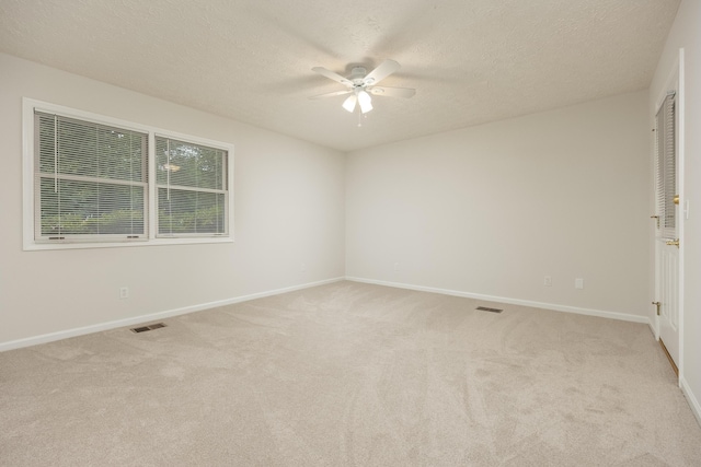 spare room with ceiling fan, light colored carpet, and a textured ceiling