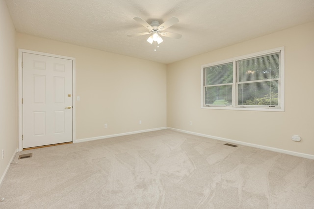 unfurnished room featuring a textured ceiling, ceiling fan, and light carpet