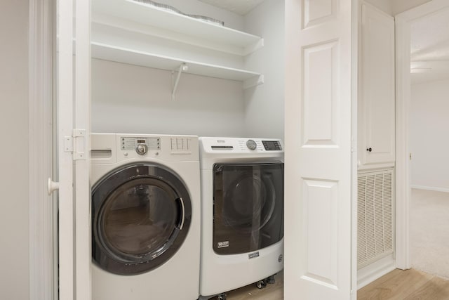 laundry room with light hardwood / wood-style flooring and washing machine and clothes dryer